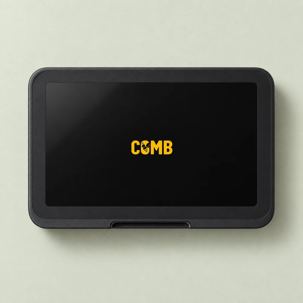 Illustrative straight overhead view of Comb Studio, a wide black touchscreen terminal with a small yellow Comb logo, on a sage surface.
